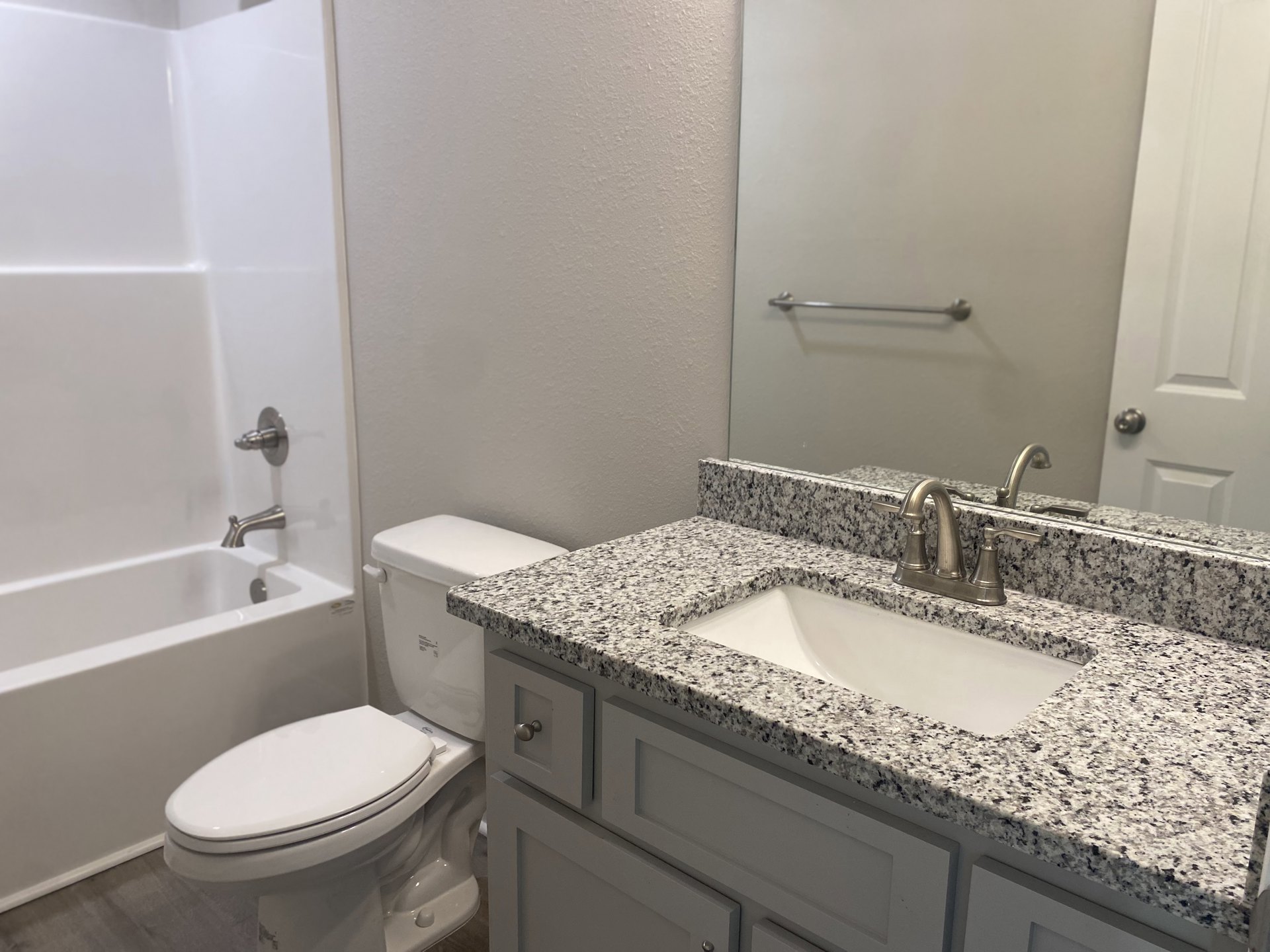 Modern bathroom featuring a white ceramic sink with chrome faucet, wall-mounted mirror, white toilet, glass-enclosed shower, and light tile flooring