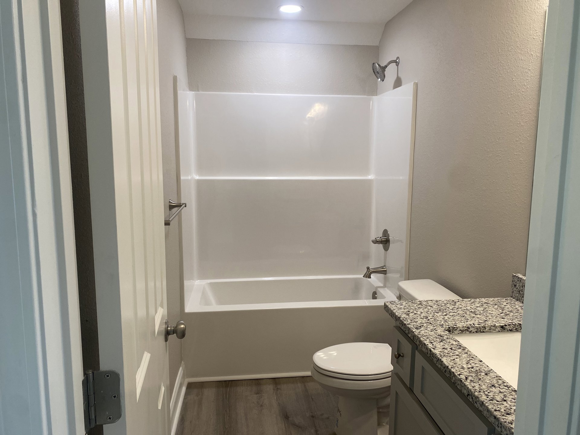 Bathroom with white bathtub, closed toilet, wall-mounted metal towel bar, and tiled walls