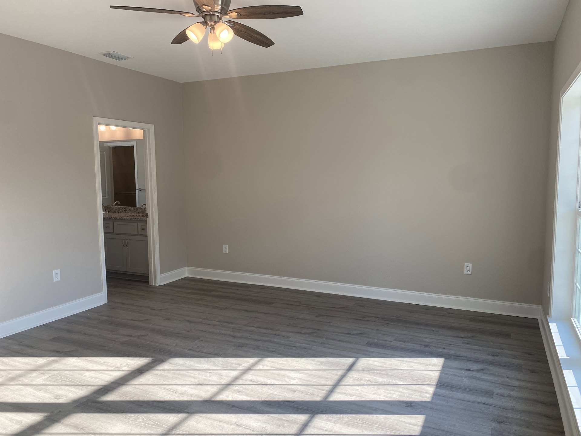 Ceiling fan with light fixture above wood flooring, white walls, window, bathroom vanity with sink and mirror, close-up of cabinet, plaster ceiling with molding