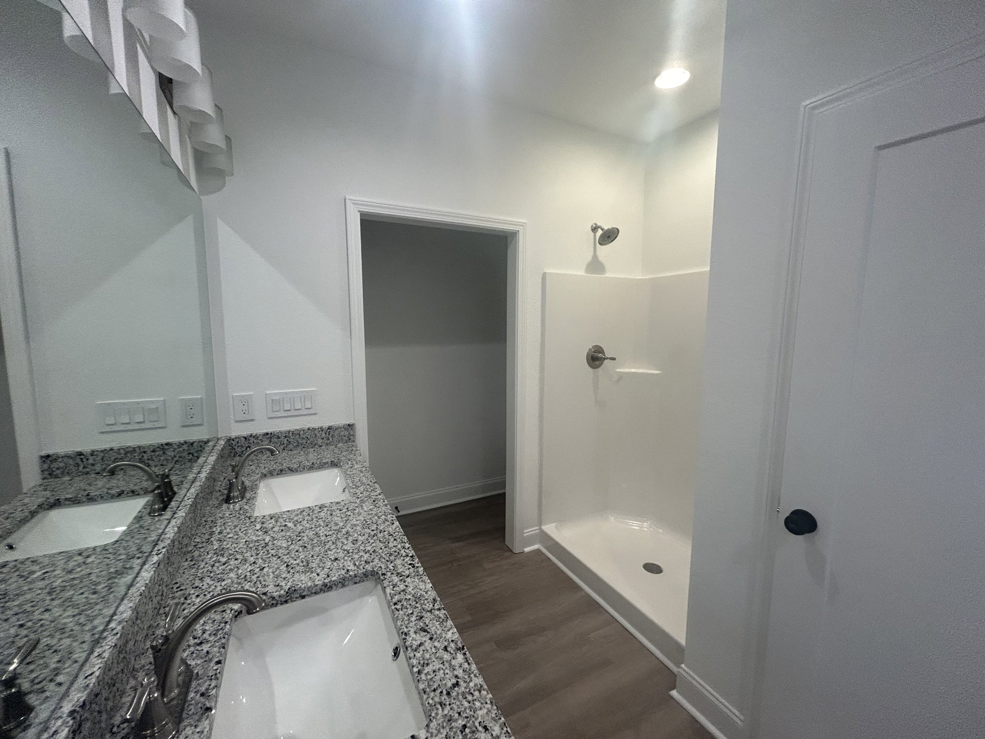 Bathroom with marble countertop and undermount sink, chrome faucet, white door with black trim, ceiling light, grey tile floor, white paper on marbled surface