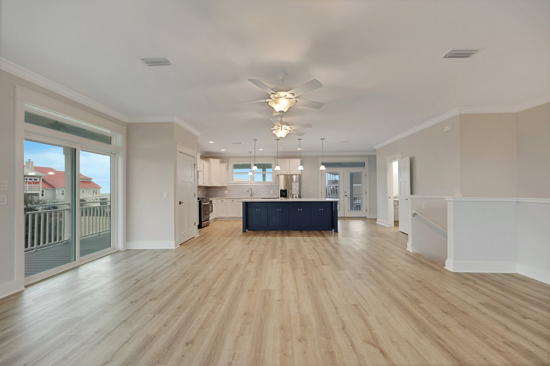 Open kitchen with blue island featuring white countertops, wood flooring, ceiling fan with light fixture, large window overlooking neighboring houses, plaster walls and laminate
