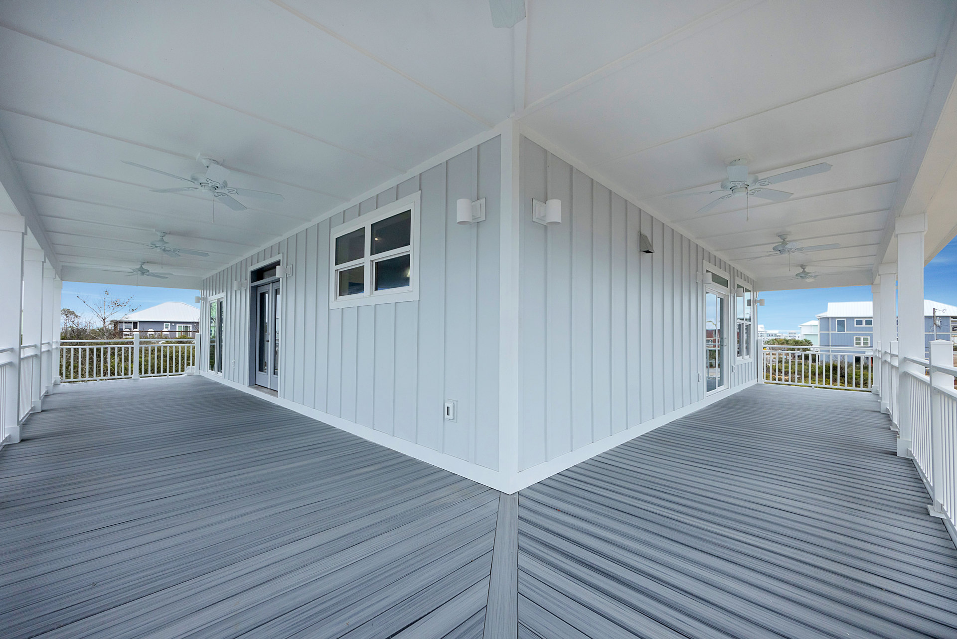 White house exterior with wood deck, large window with white frame, white wall-mounted lamp, and light switch on smooth white wall.
