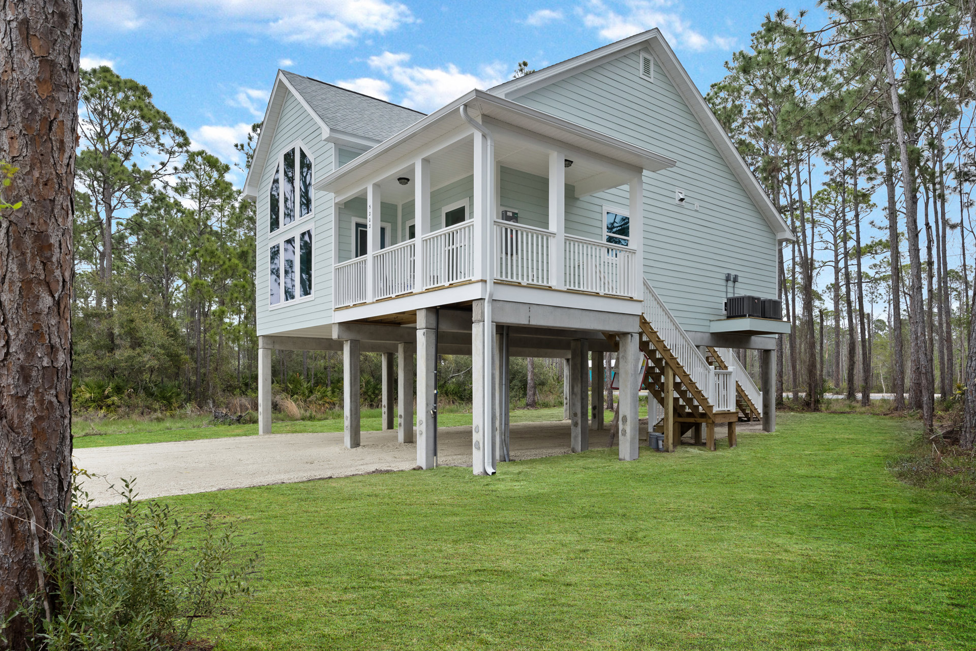 White house with covered porch, wooden stairs with white railings, concrete walkway leading through grass lawn, mature trees and Ronald Reagan Boyhood Home visible in the