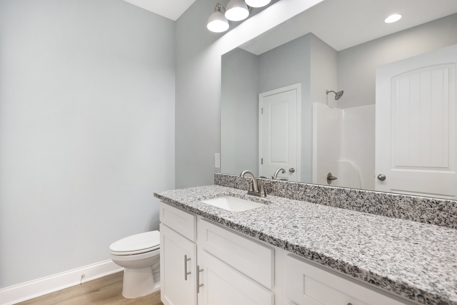 Marble countertop with undermount sink, chrome faucet, white toilet, white paneled door, light tile flooring, and neutral wall paint