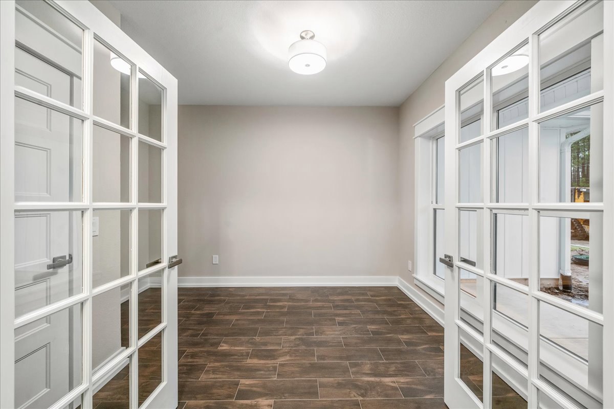 White paneled doors, wood plank flooring, white baseboards, glass-paned door, white walls, ceiling light fixture
