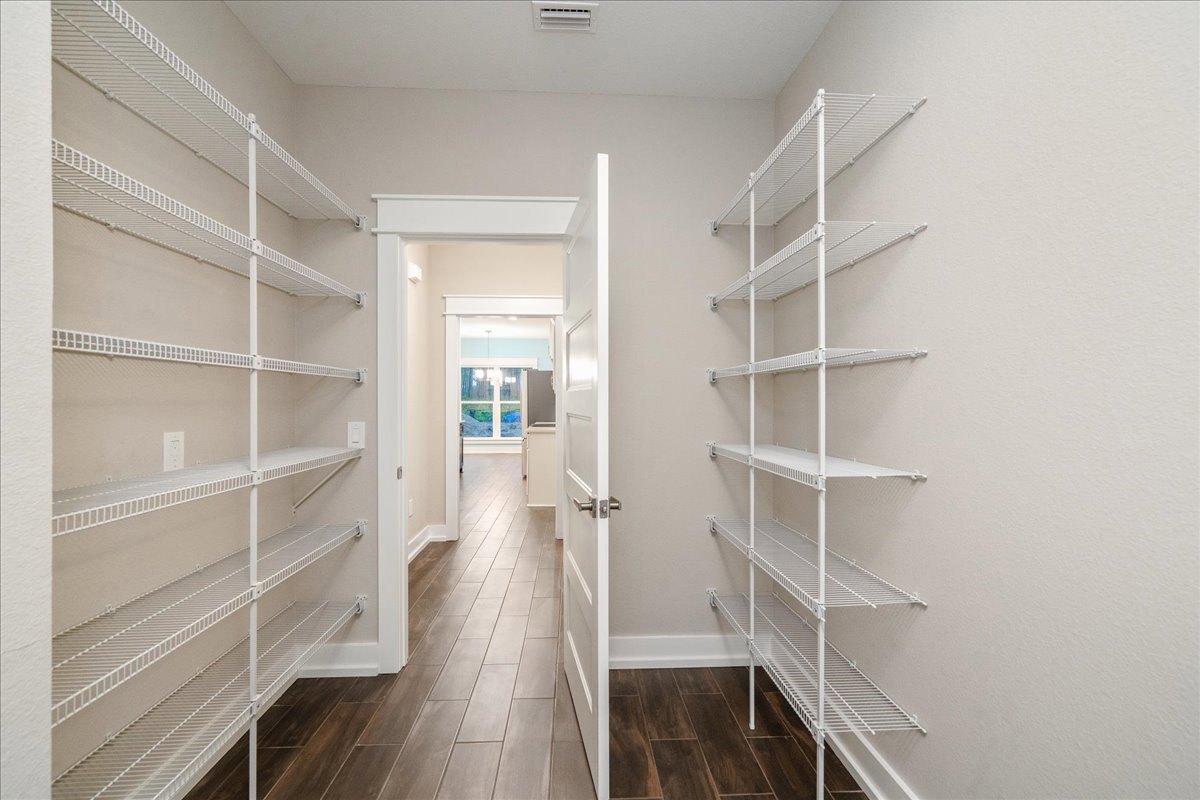 Built-in white shelves along a plaster wall, wood flooring, window with natural light, minimalist interior design