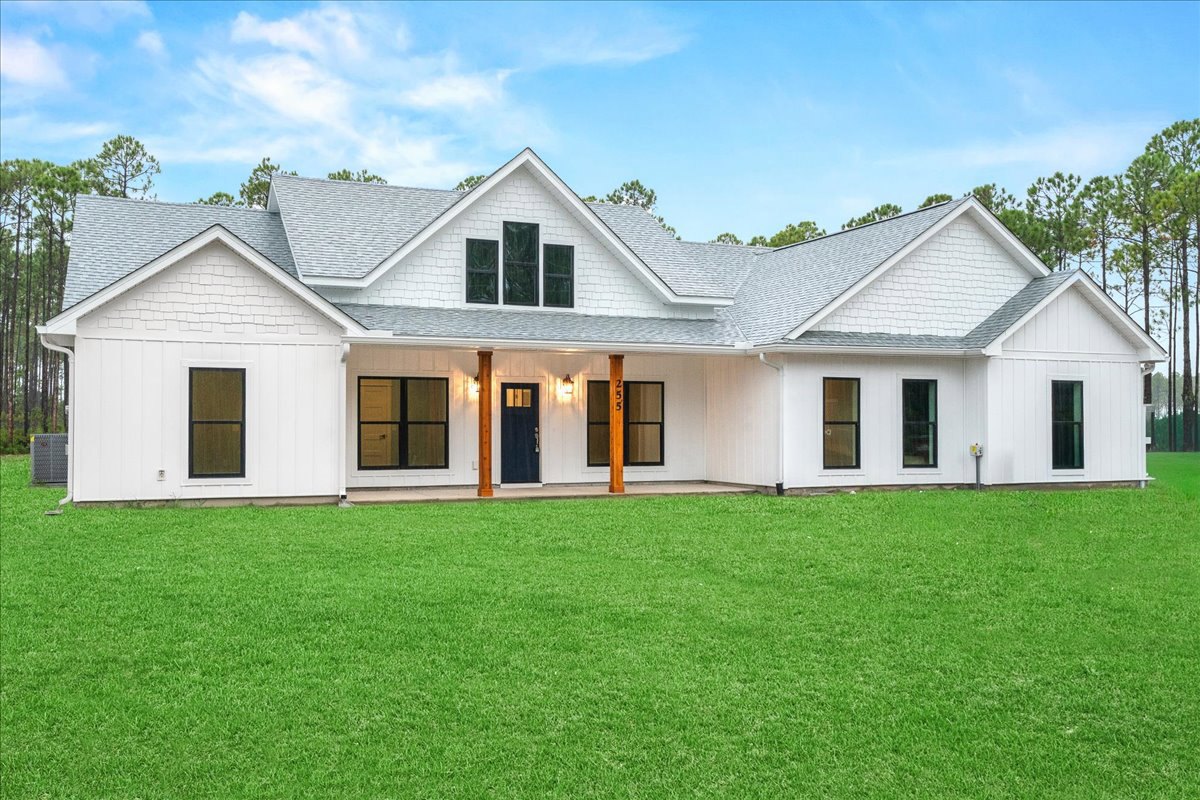 White house with blue door and multiple windows, surrounded by green lawn, Robert Frost Farm visible in the background, cloudy sky overhead