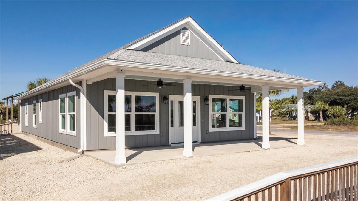 White siding home with covered porch, white columns, wooden railing, ceiling fan, white framed windows, and glass-paneled front door.