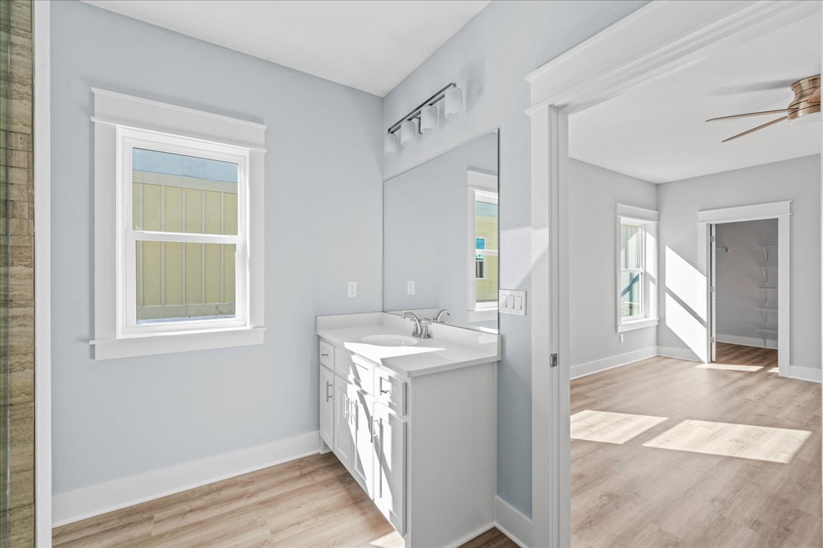 White bathroom with rectangular mirror above a modern sink, light wood cabinetry, white walls, and built-in shelving.