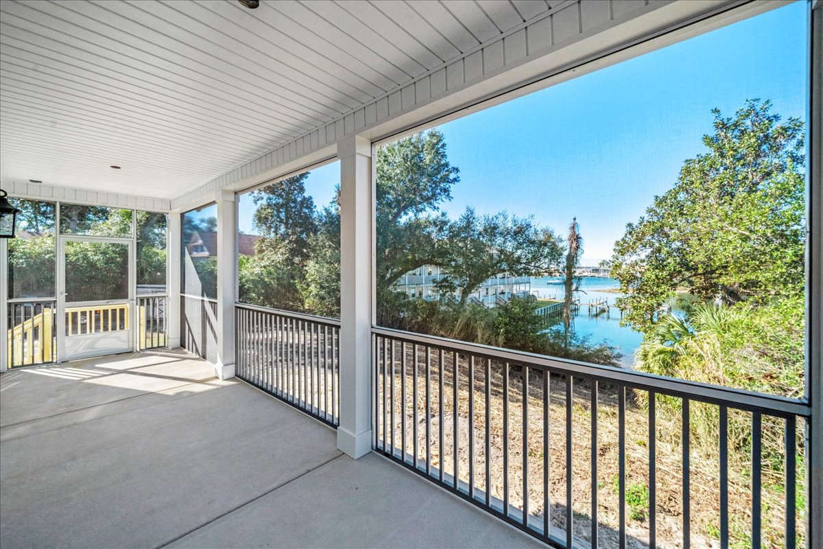 Expansive white porch with railing overlooking water and surrounding trees, shaded deck area, clear sky in background