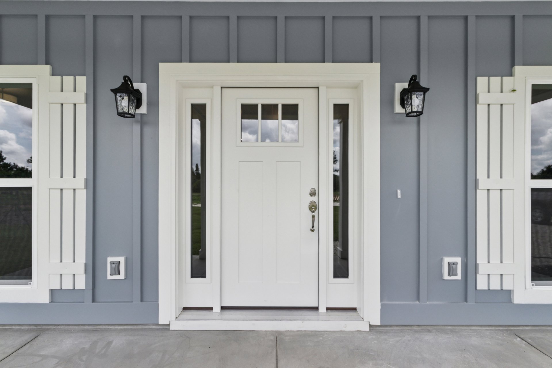 White front door with vertical glass panels, silver door handle, and adjacent white trim