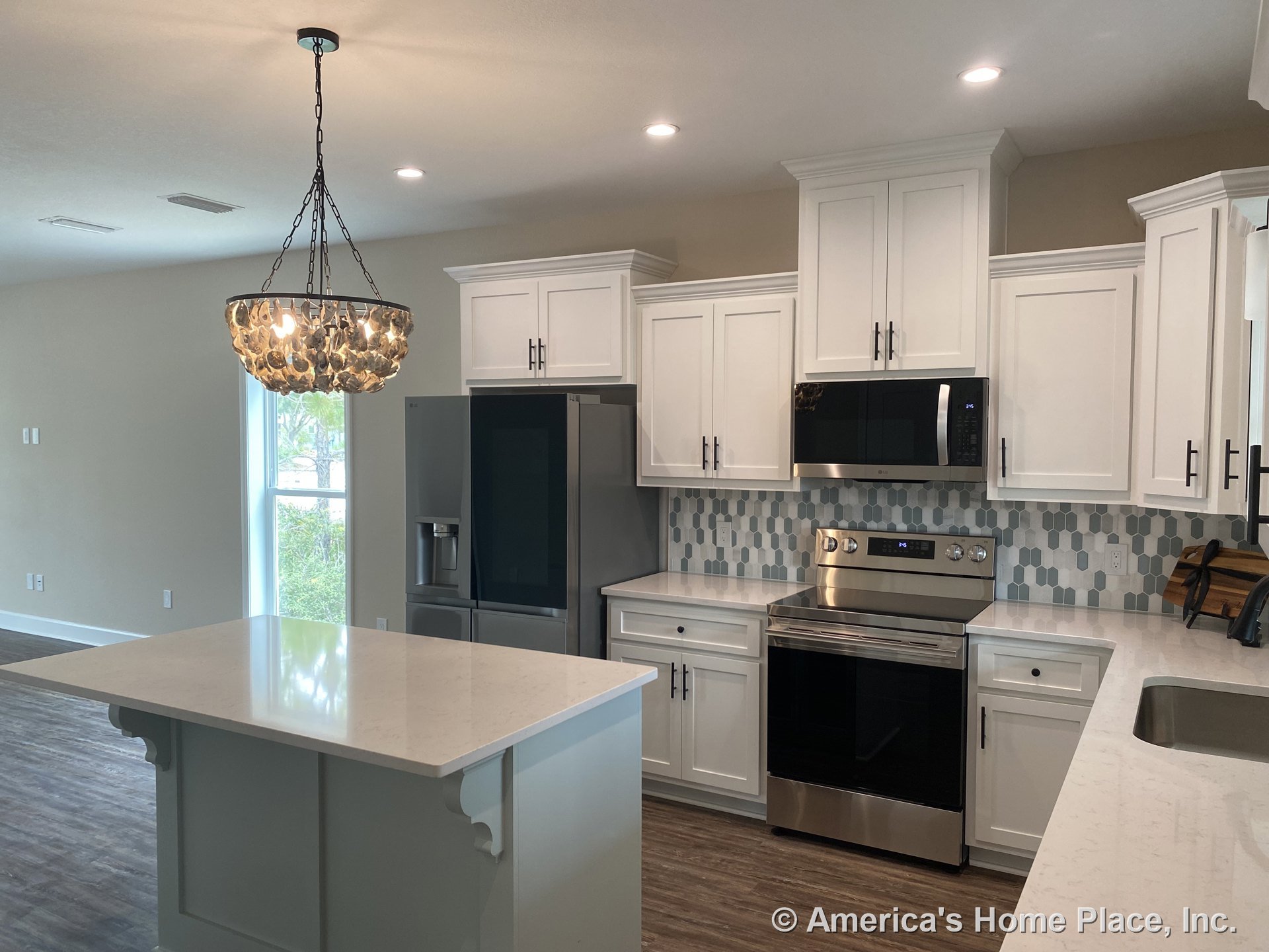 White shaker cabinets and quartz countertops with a central island, hexagonal tile backsplash, stainless steel appliances including built-in microwave, range, and refrigerator