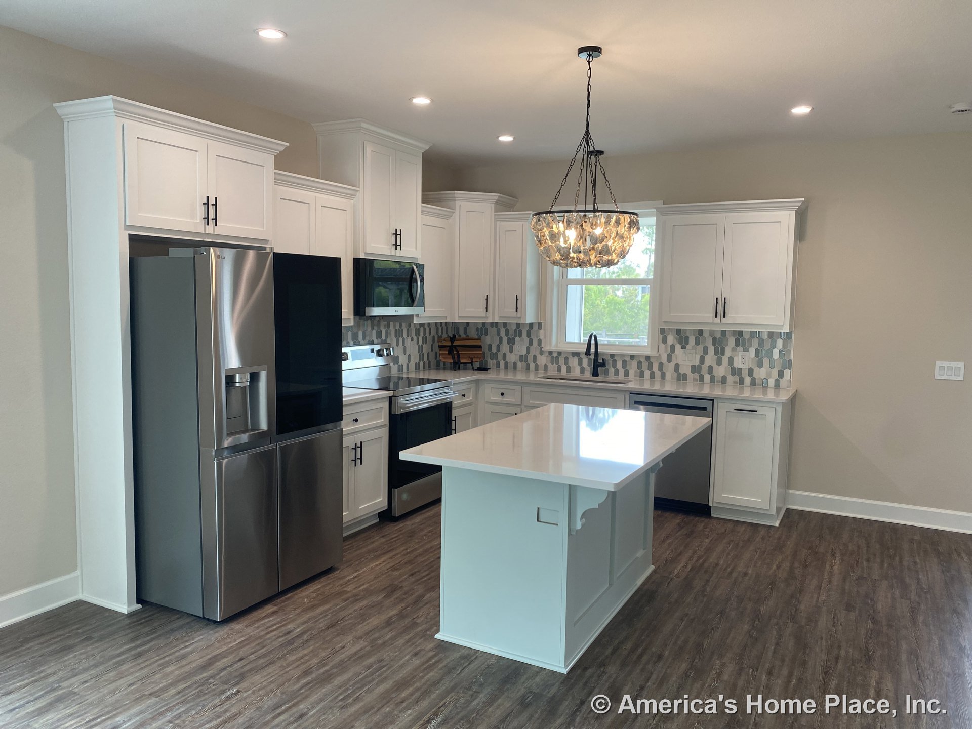White shaker kitchen cabinets, central island with quartz countertop, geometric tile backsplash, stainless steel appliances including refrigerator, built-in microwave, electric