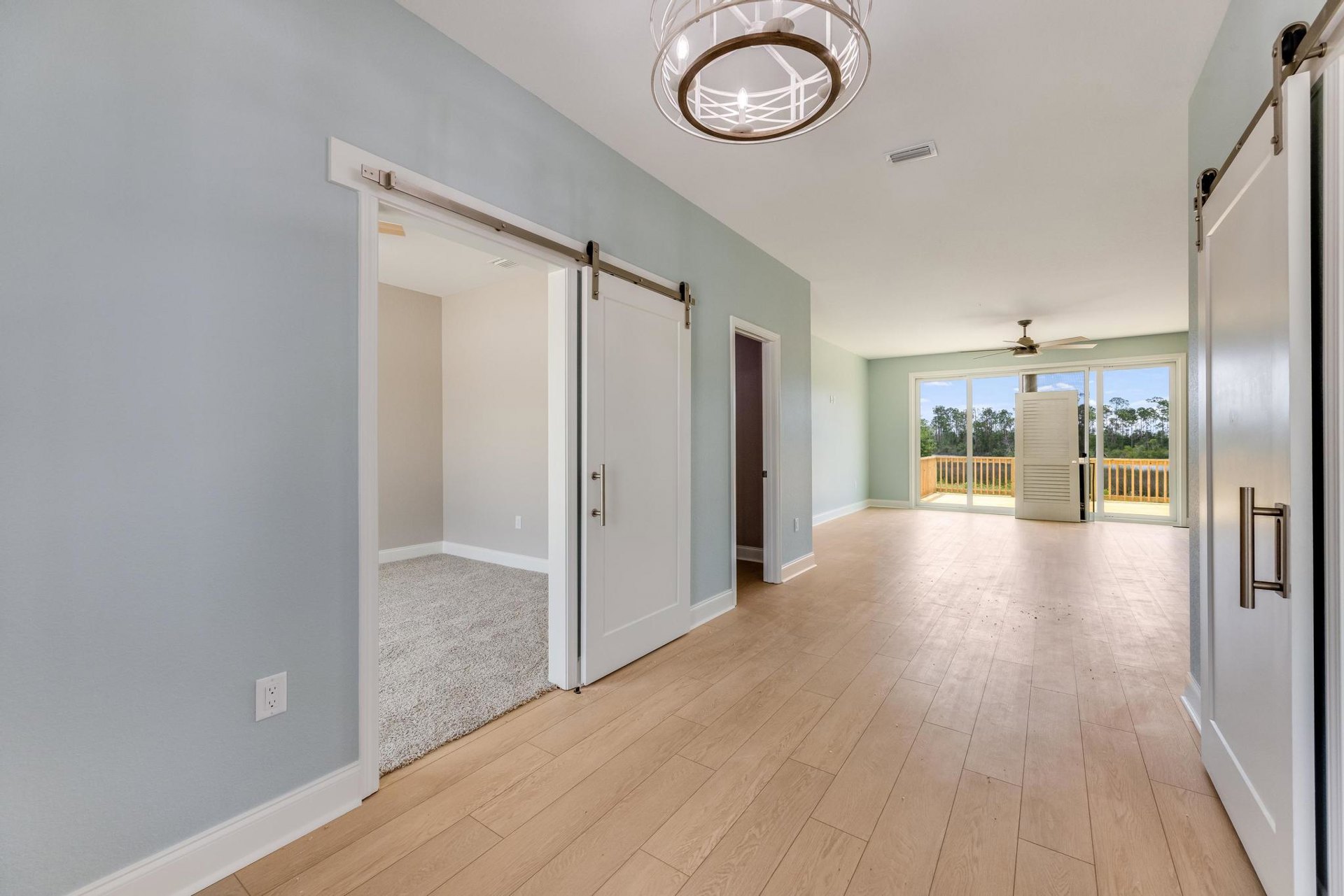 White paneled door with brushed metal handle, wood laminate flooring, white plaster walls, ceiling fan with circular wood-trimmed light fixture