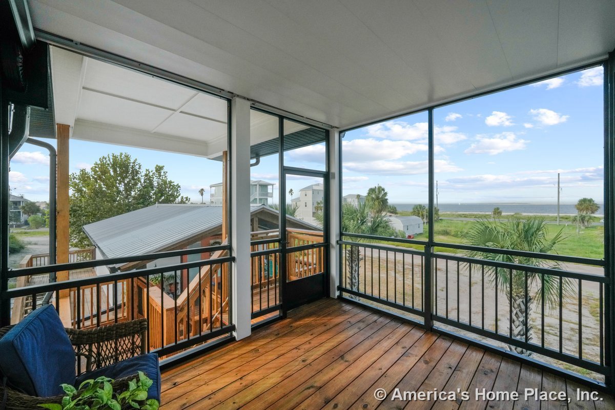 Screened porch with wood plank flooring, metal railing system, covered ceiling panels, exterior stair access, and coastal landscape view.
