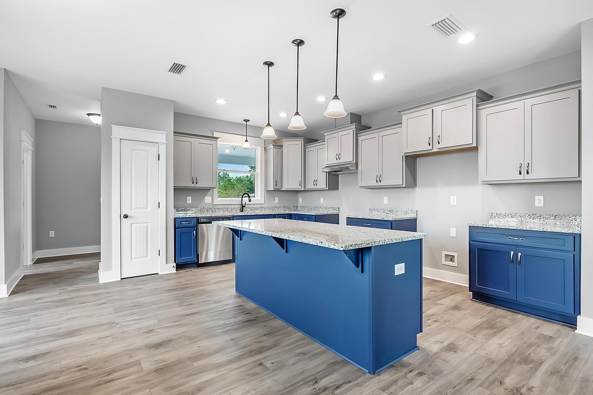 Blue kitchen island with marble countertop, white shaker cabinets with silver handles, stainless steel appliances, white framed window, pendant light with black pole, light