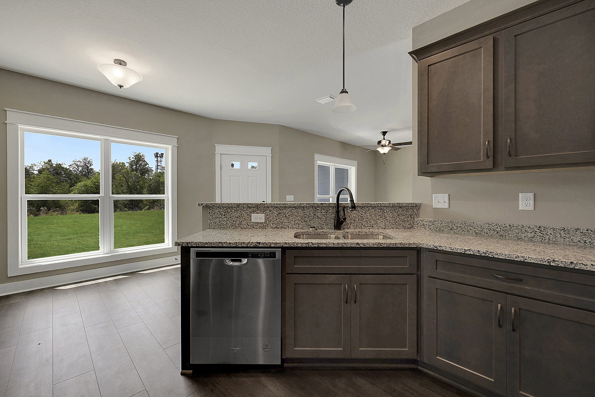 Modern kitchen with white cabinetry, stainless steel dishwasher, undermount sink, chrome faucet, quartz countertop, large window overlooking grassy field, and pendant light fixture