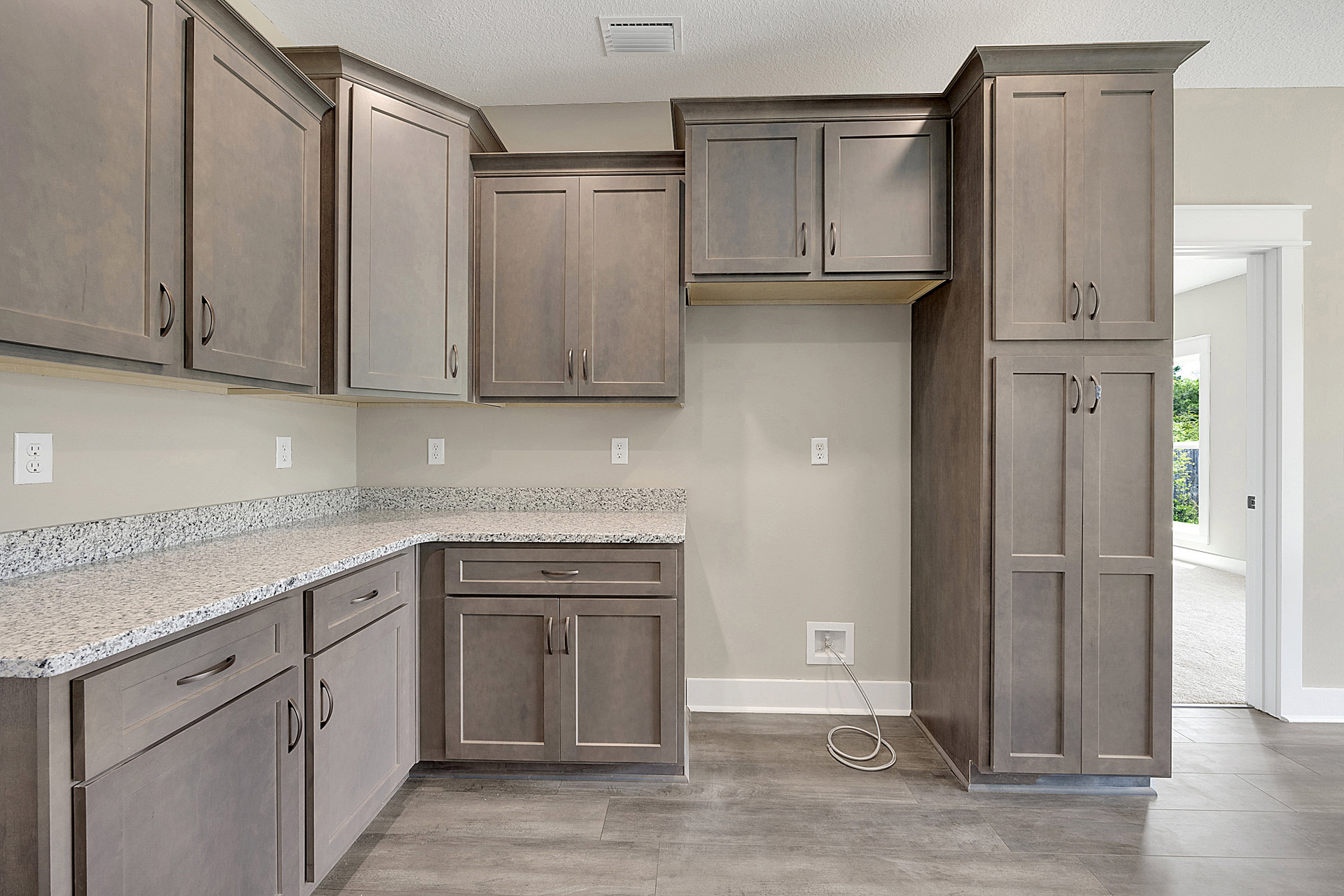 Gray shaker cabinets, marble countertops, stainless steel sink, white tile backsplash, built-in appliances, and brushed metal hardware in a modern kitchen.