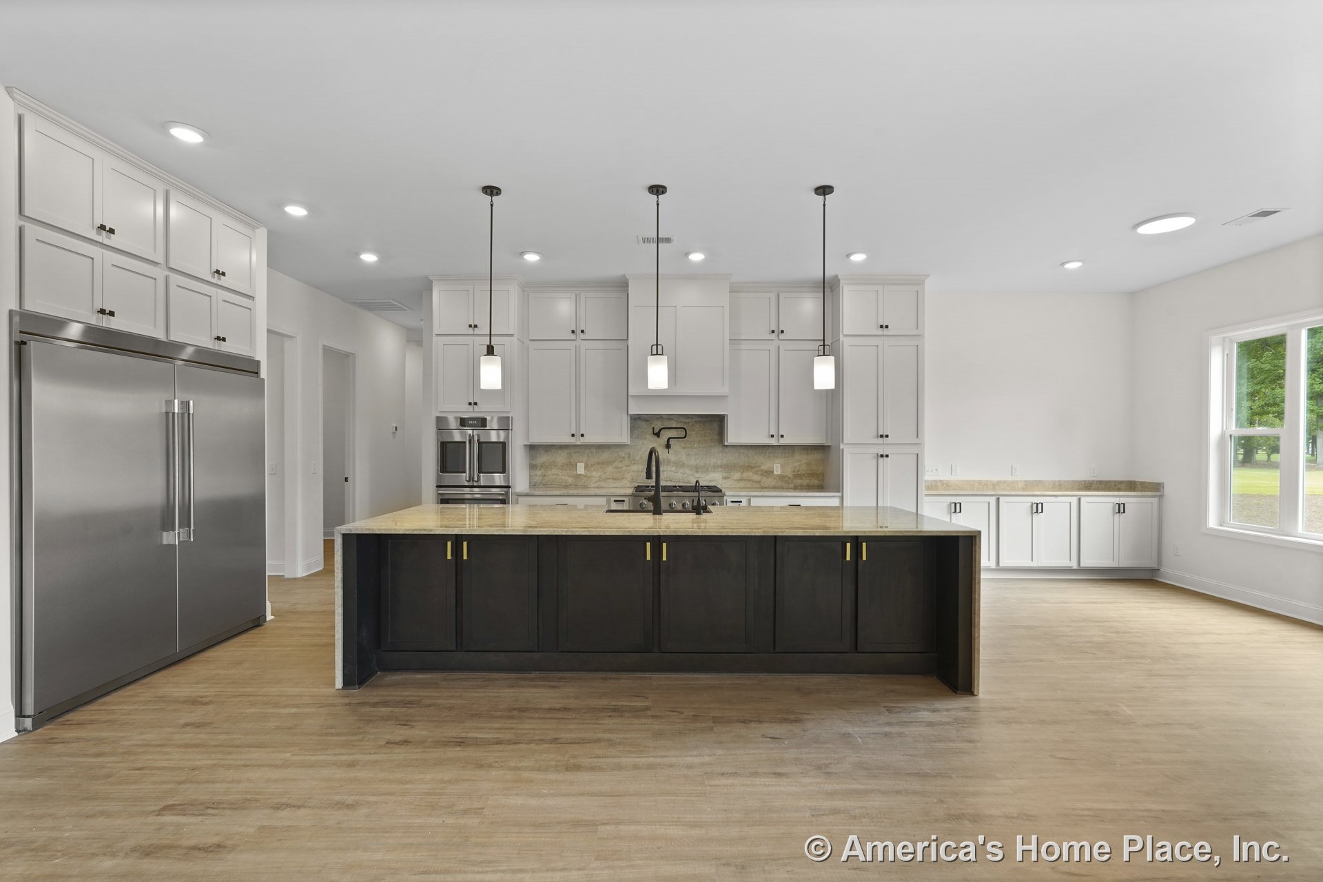 Spacious kitchen with large central island featuring dark cabinetry and light countertops, white shaker cabinets, double stainless refrigerator, built-in double oven, wood-look