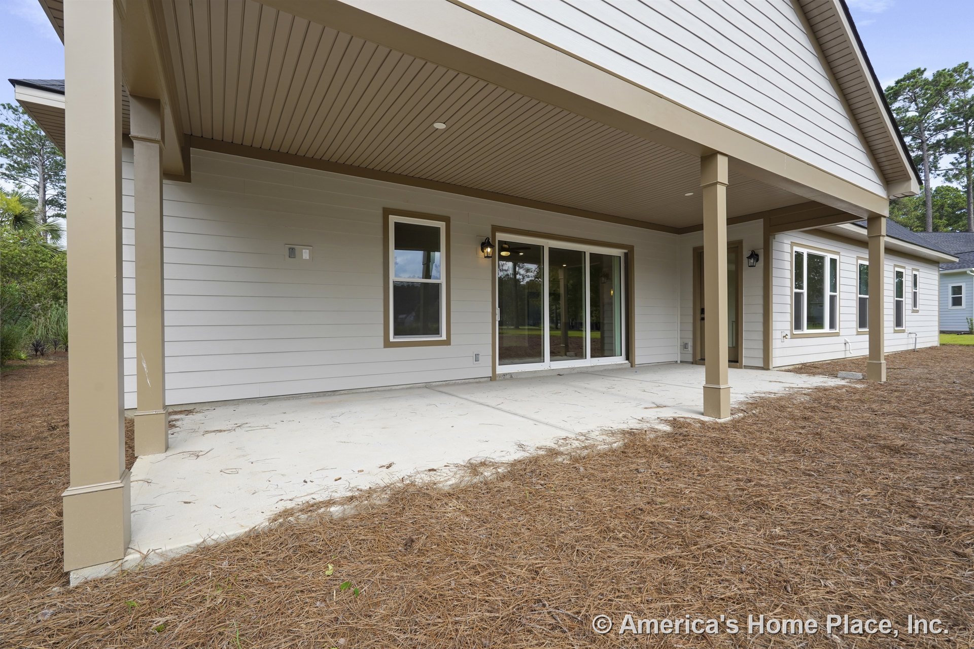 Covered rear patio with concrete slab flooring, horizontal lap siding, sliding glass doors, multiple exterior windows, recessed ceiling lighting, structural columns, trim details