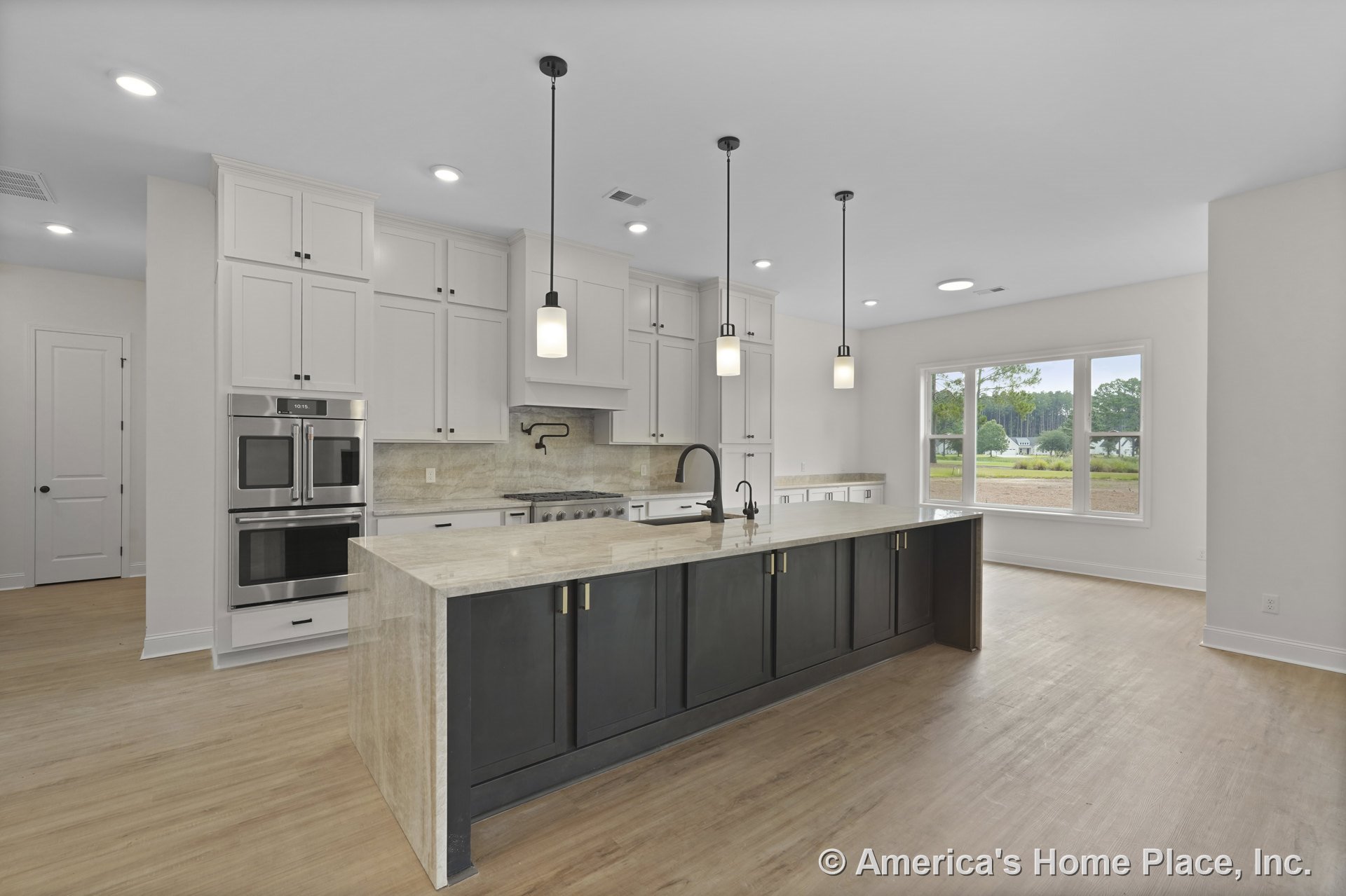 Spacious kitchen with stone countertop island, white upper cabinets, black lower cabinetry, built-in double ovens, pendant and recessed lighting, wood-look flooring, wall-mounted
