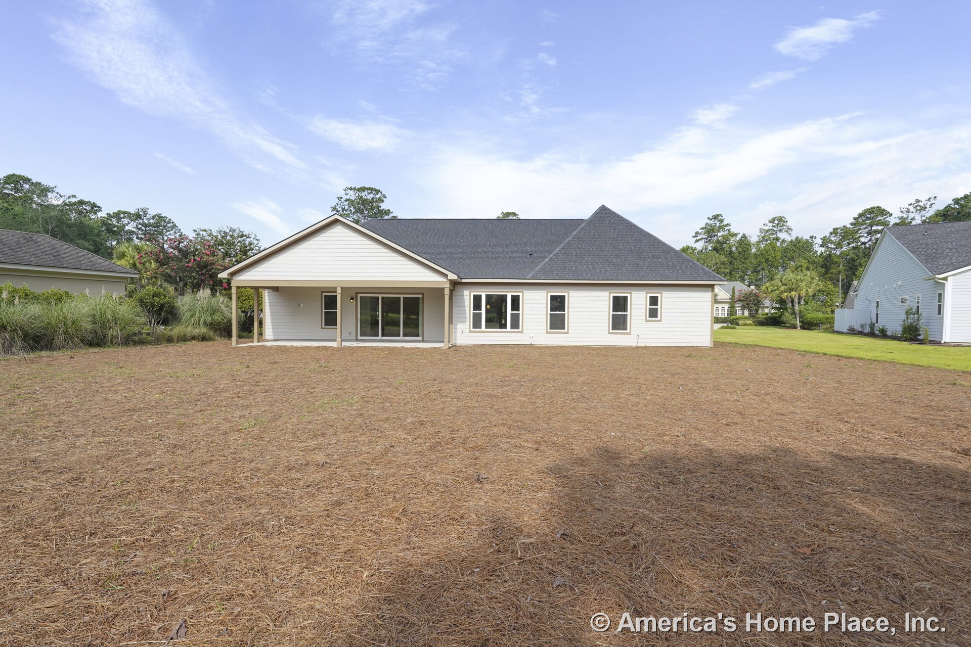 Covered rear patio with sliding glass doors, multiple large rectangular windows, white horizontal siding, dark shingle roof, and spacious backyard.