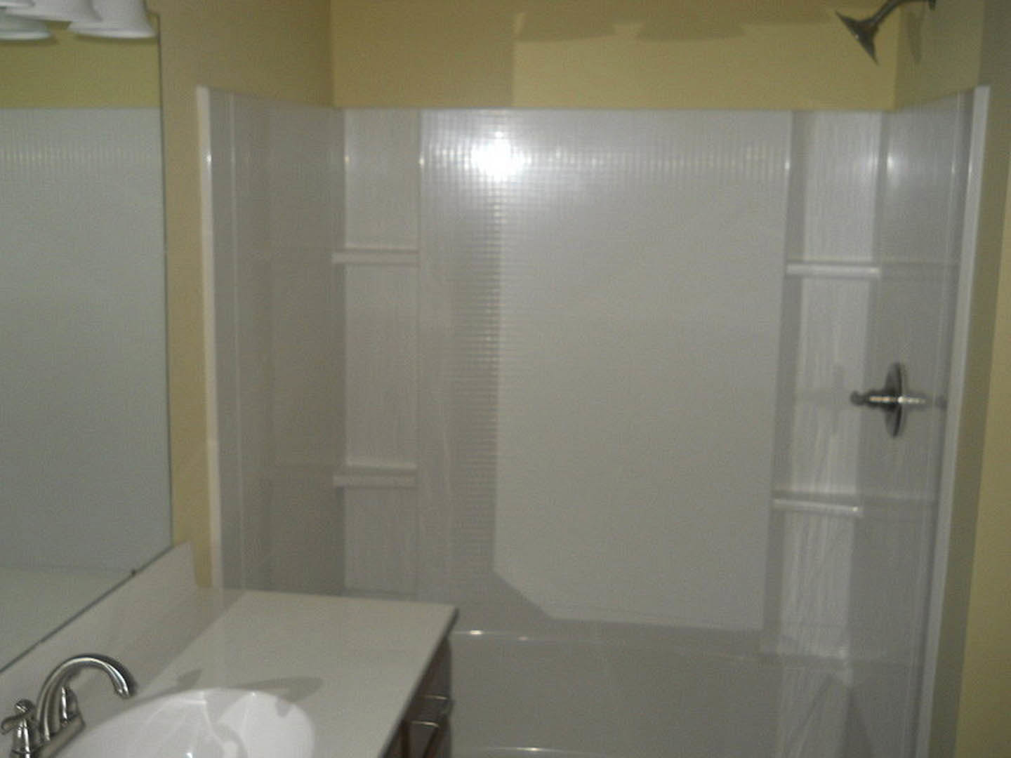 Modern bathroom featuring a white tile shower, wall-mounted sink with chrome faucet, and large mirror above the vanity