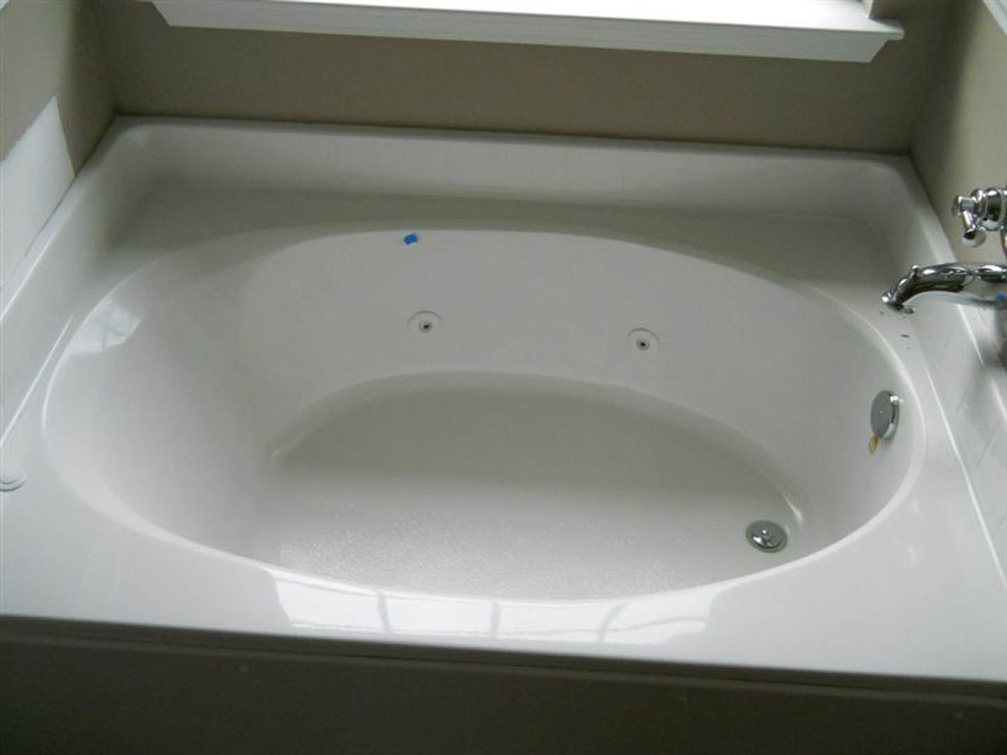 Freestanding white bathtub with silver faucet against light-colored bathroom wall