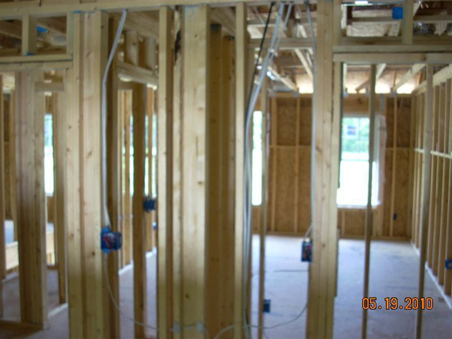 Exposed wood beams and planks with visible insulation and electrical wiring inside a partially constructed room