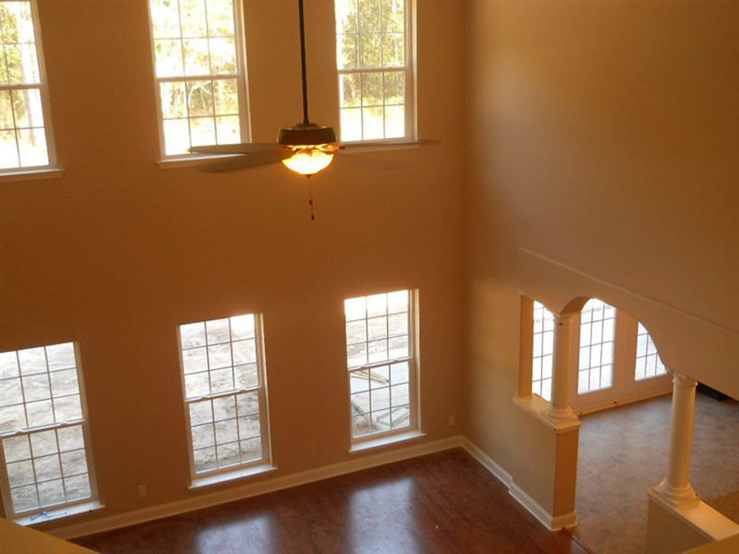 Ceiling fan with brushed metal finish mounted above wooden flooring, white-framed windows revealing snowy landscape, recessed ceiling light, neutral walls