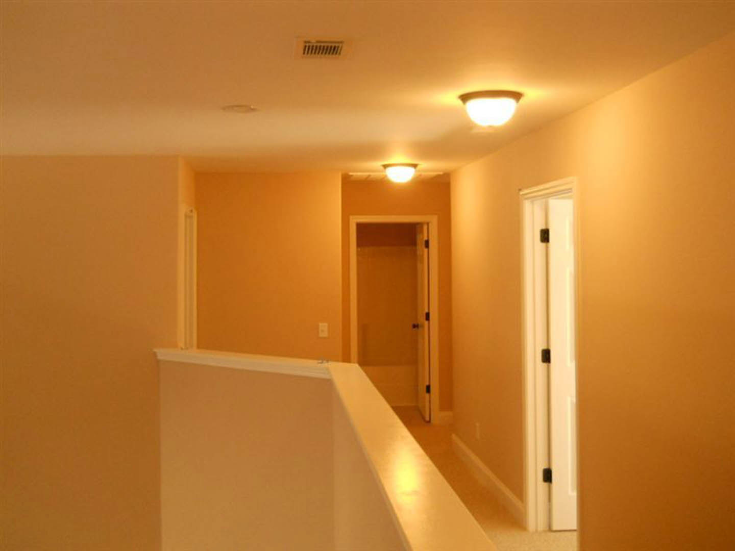 Hallway with white painted railing, white paneled door, light-colored walls, and ceiling molding