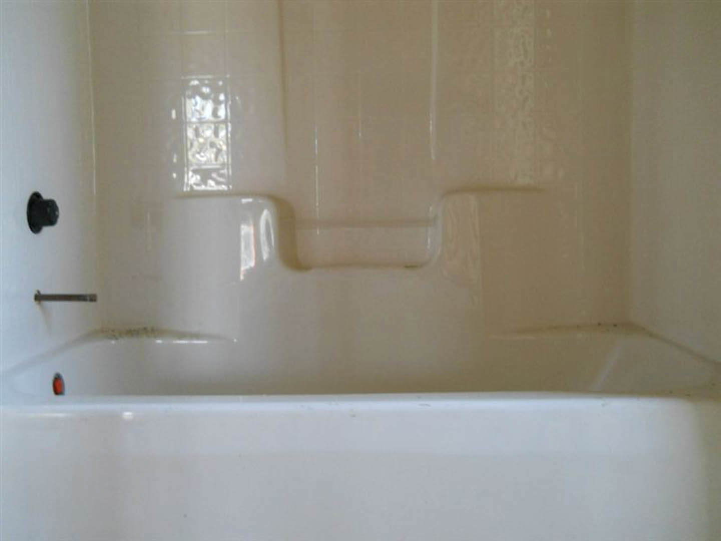Freestanding white bathtub with silver faucet against tiled bathroom wall