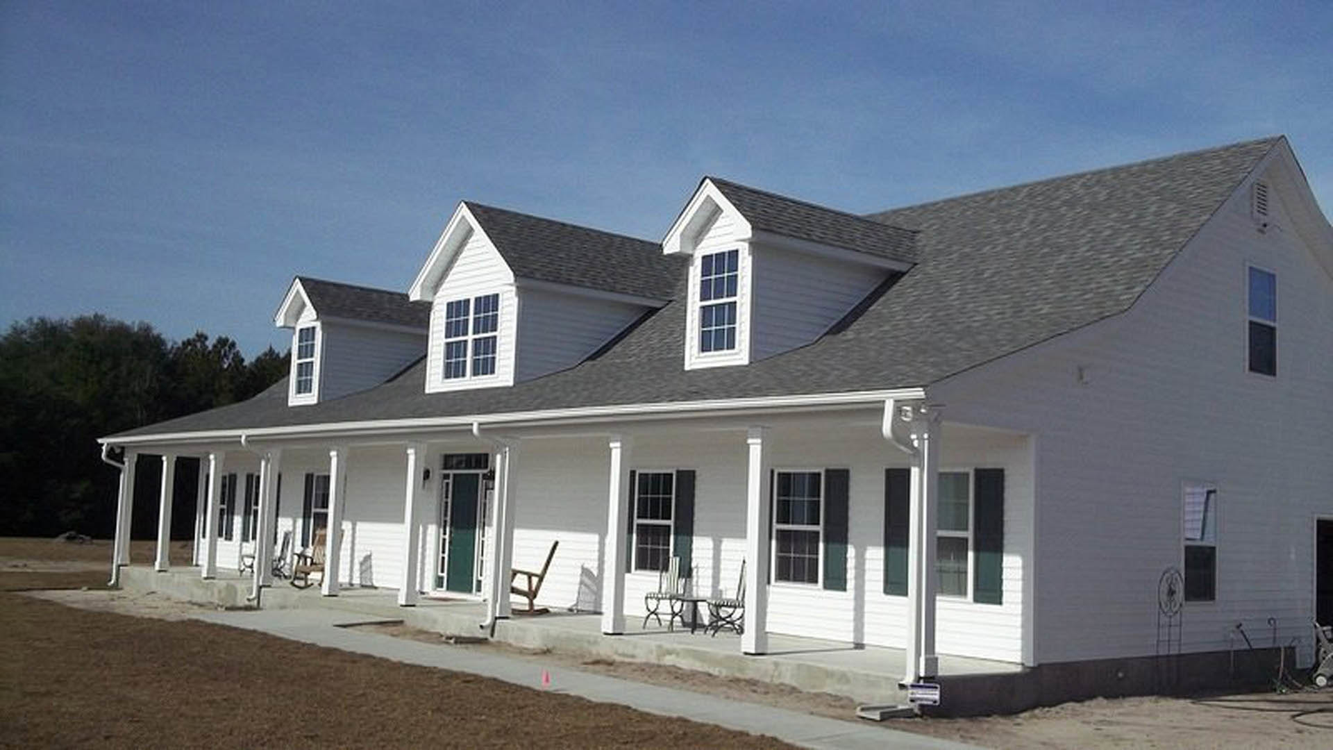 White siding house with white columns, small porch, several windows, and a sidewalk leading to the entrance