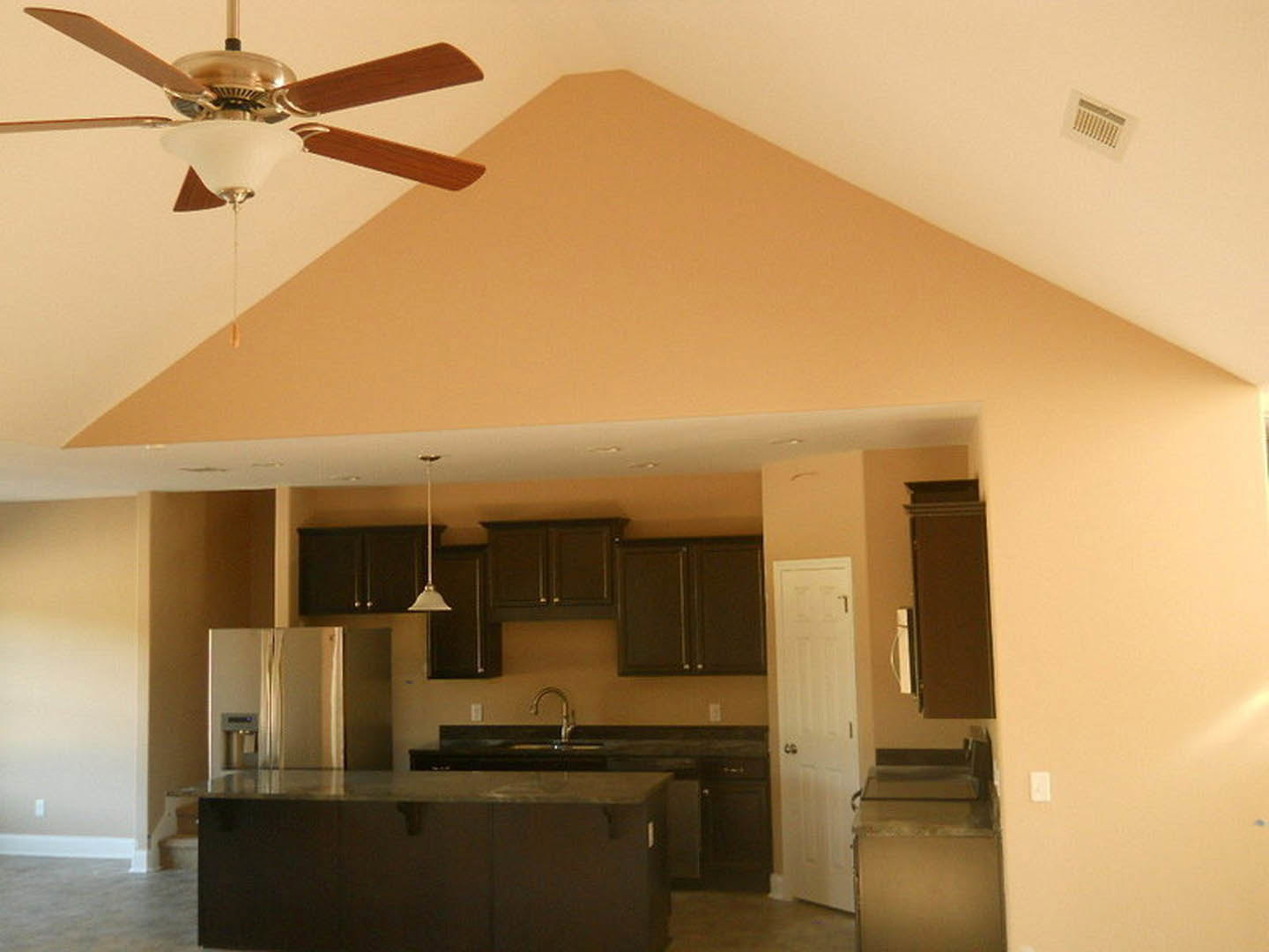 Modern kitchen with white cabinetry, glass dining table, ceiling fan with light fixture, stainless steel refrigerator, and white door with silver handles