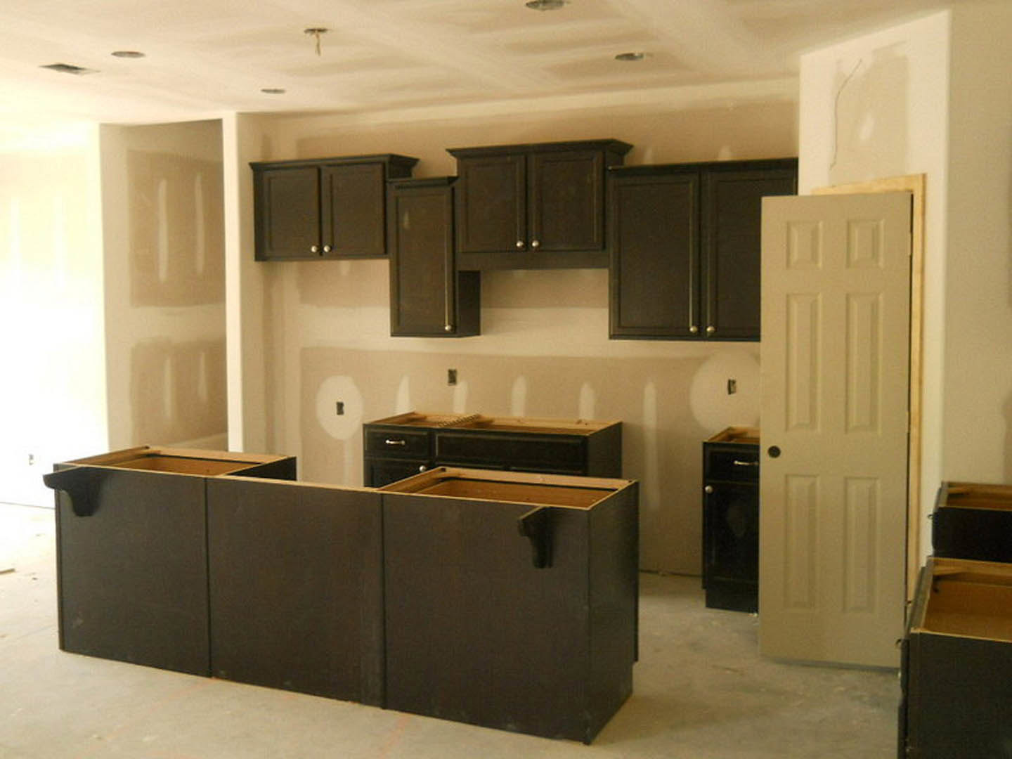 Kitchen with matte black cabinets, white quartz countertop, stainless steel sink, and light wood flooring