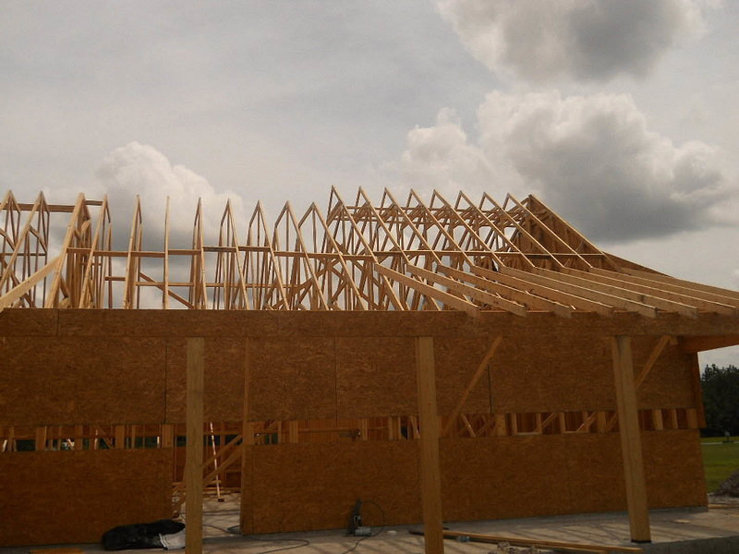 Wood-framed exterior structure under construction beneath cloudy sky