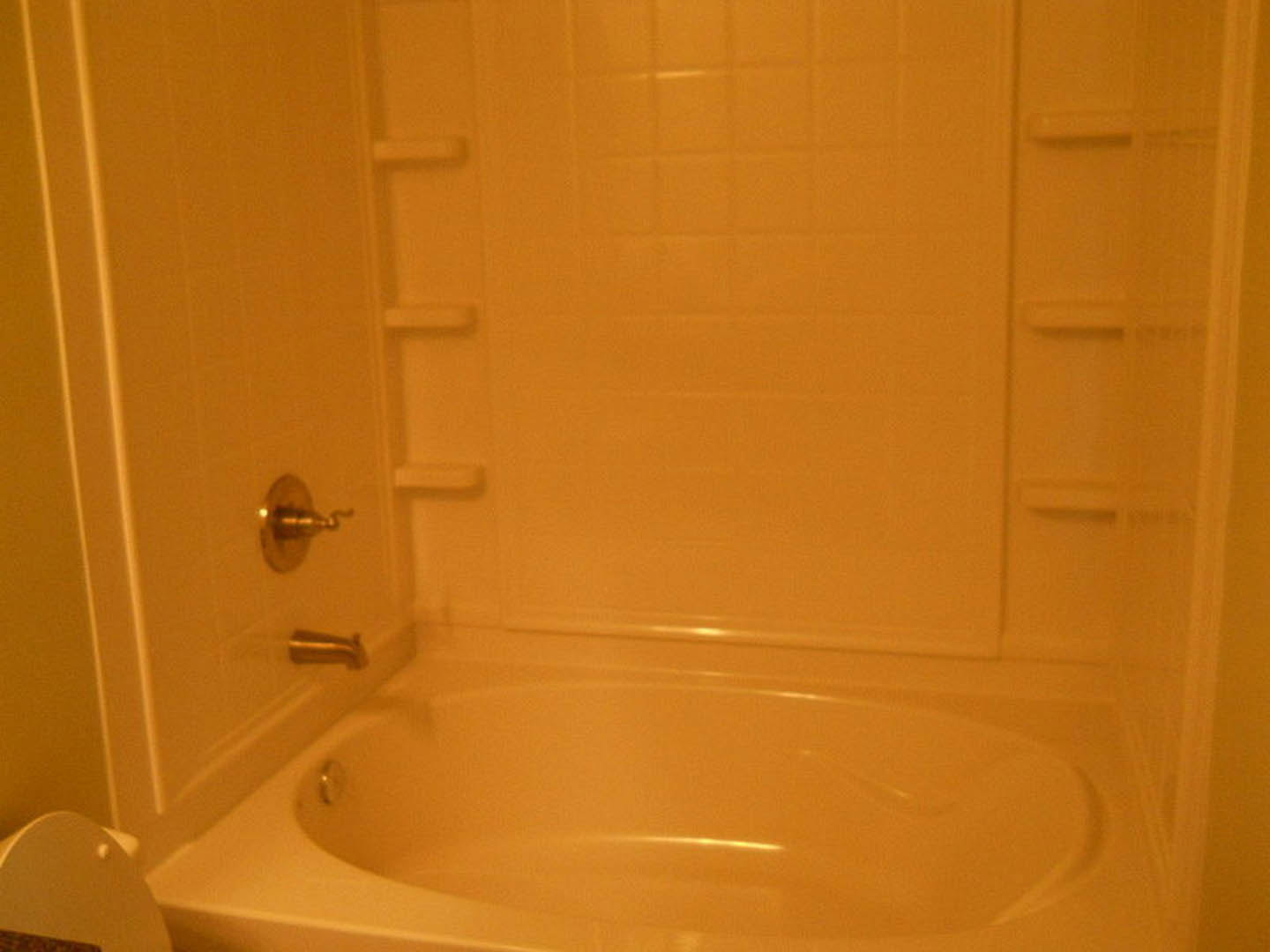 Freestanding white bathtub with chrome faucet, surrounded by light-colored tile walls and floor in a modern bathroom