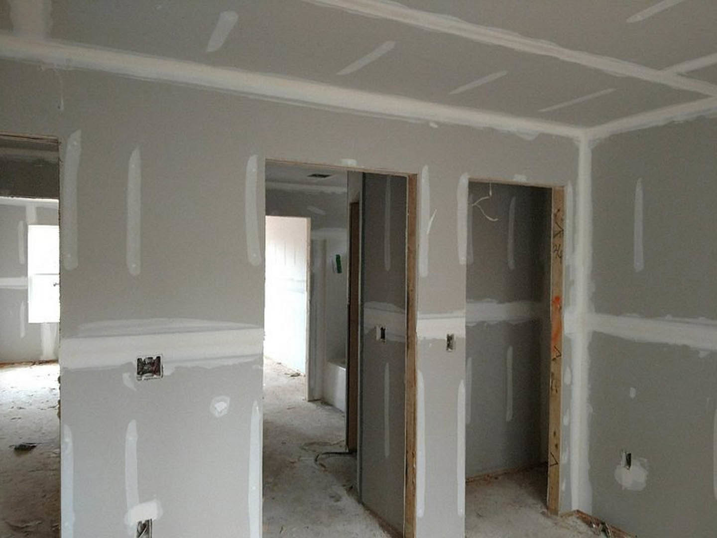 White-walled room with white trim, doorway, and close-up window featuring a hole; white cabinet with logo sits against a white surface.