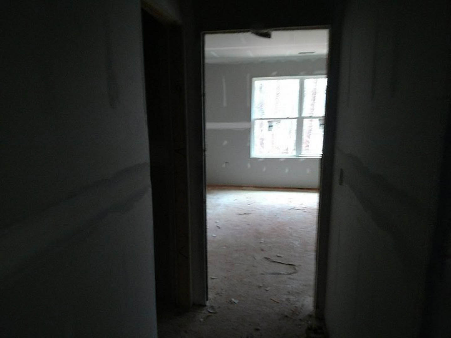 Open white door leading into a room with black accent wall bordered in white, natural daylight streaming through window, plaster walls, and modern fixtures