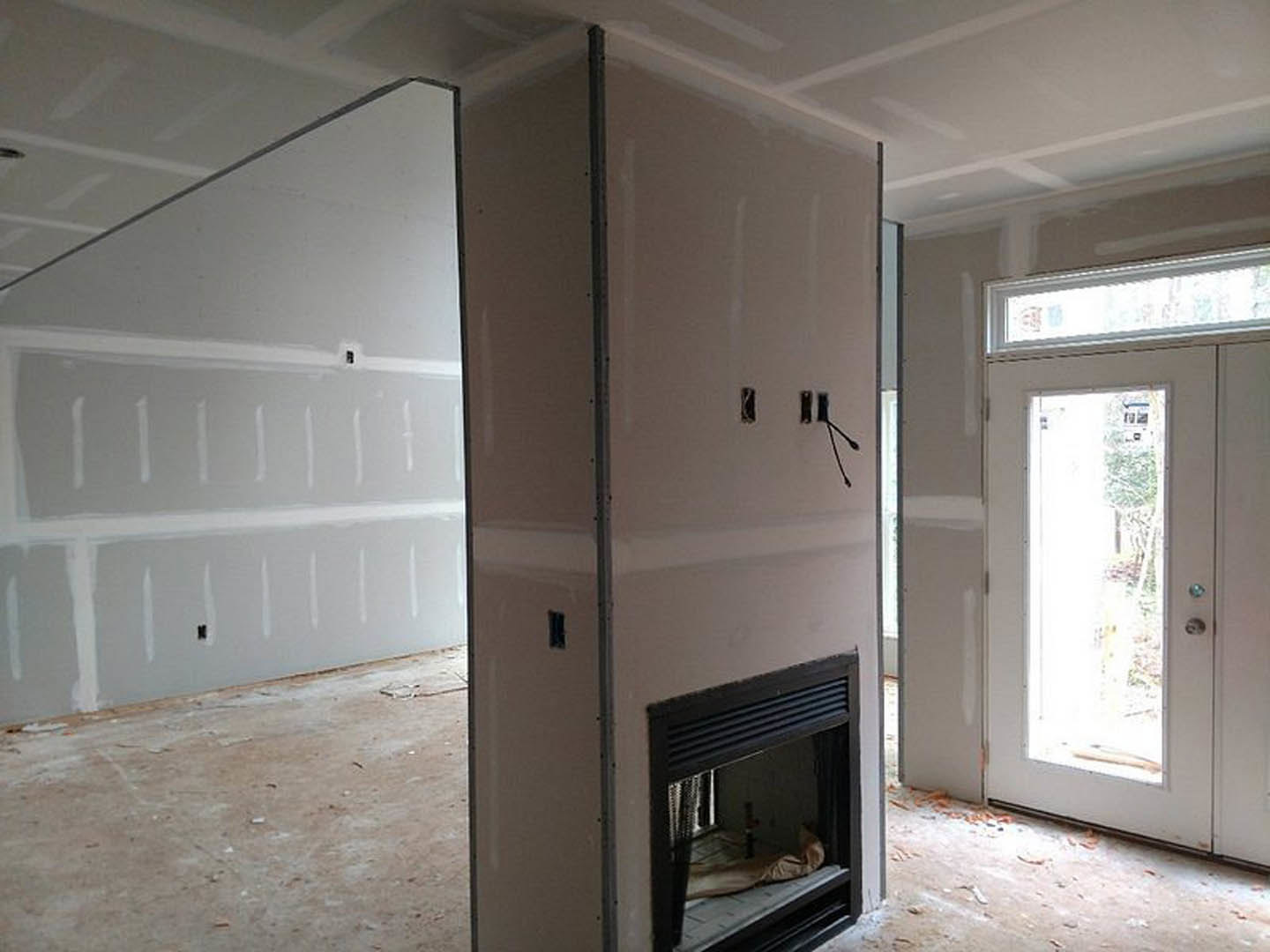Living room with white plaster walls, glass-paneled door, built-in fireplace, and hardwood floor