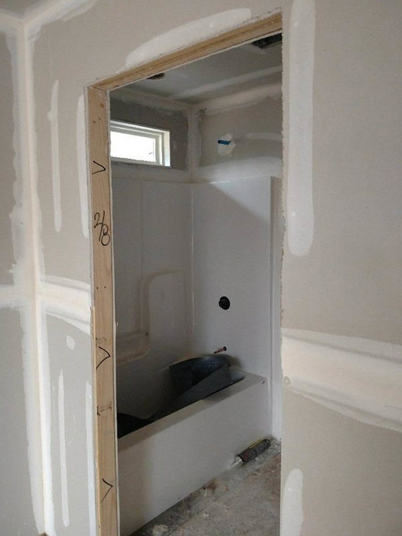 Bathroom with open white door, plaster walls, crown molding, recessed ceiling light, and modern fixtures