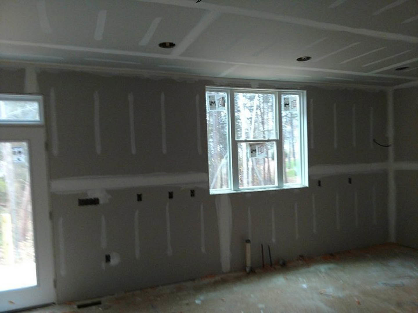 Bright room featuring two large windows, white plaster walls, wood trim, and smooth ceiling with natural daylight streaming in.