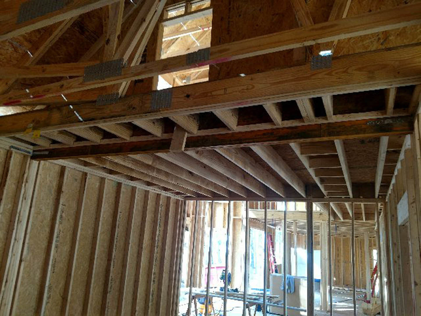 Exposed wooden ceiling beams with natural finish, plank ceiling, and visible building insulation in a residential interior