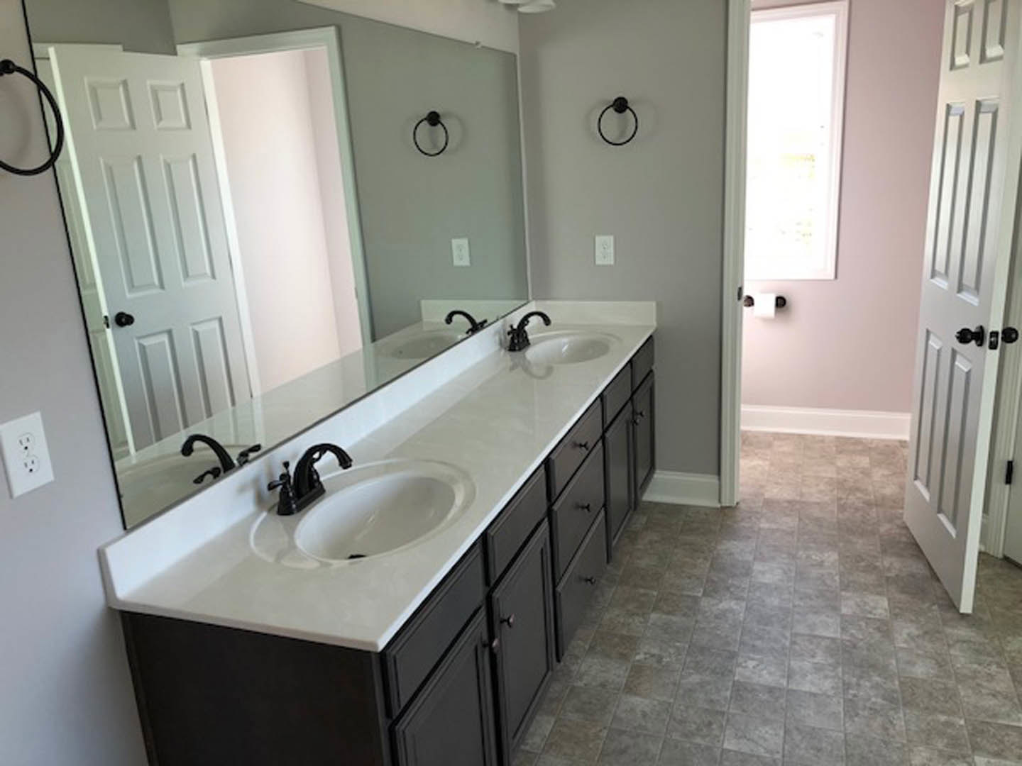 White bathroom with double sinks, marble countertop, chrome faucets, and light gray tile backsplash