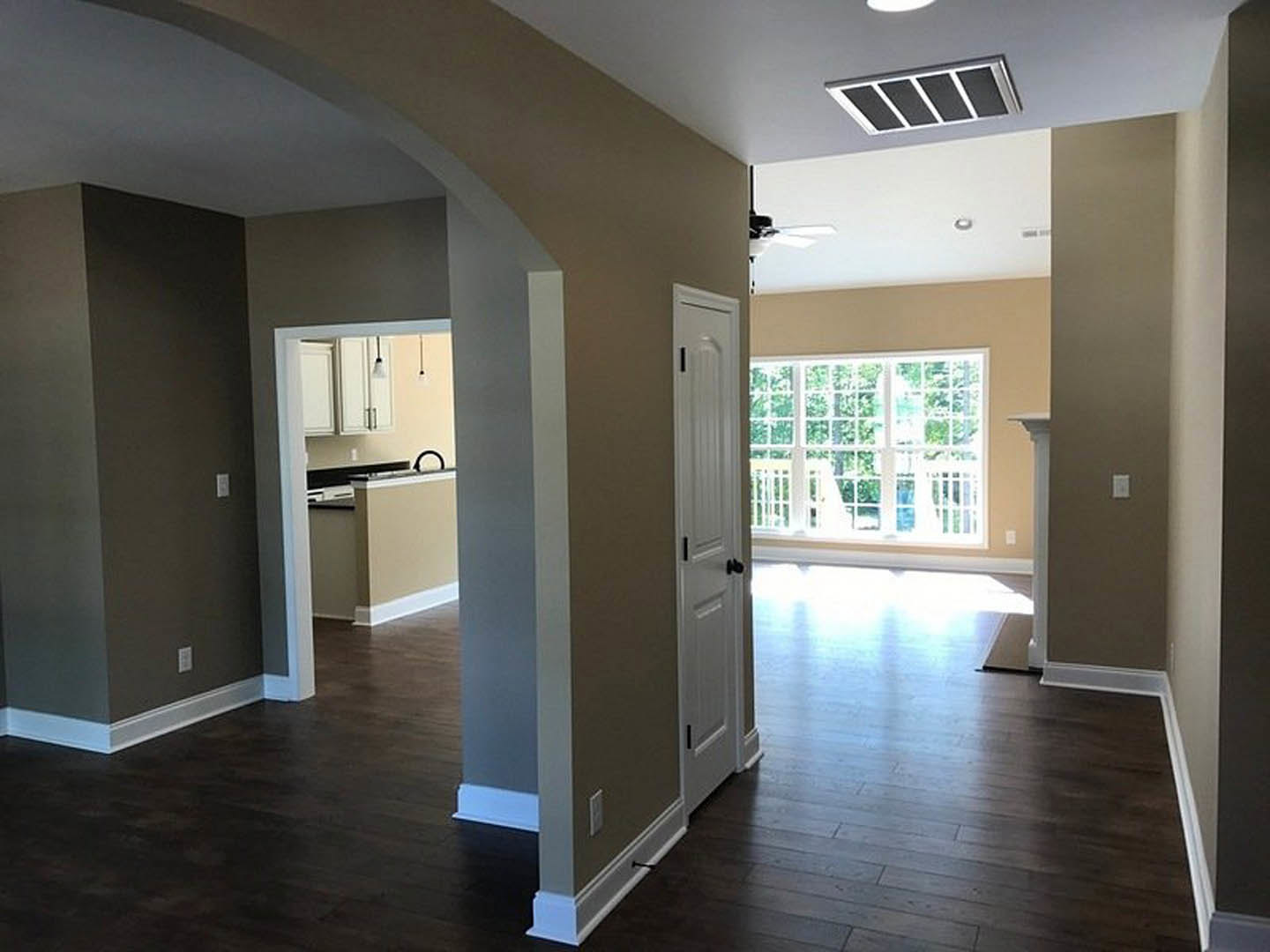 Living room featuring wide plank wood flooring, smooth white plaster ceiling, neutral walls, and a modern interior door
