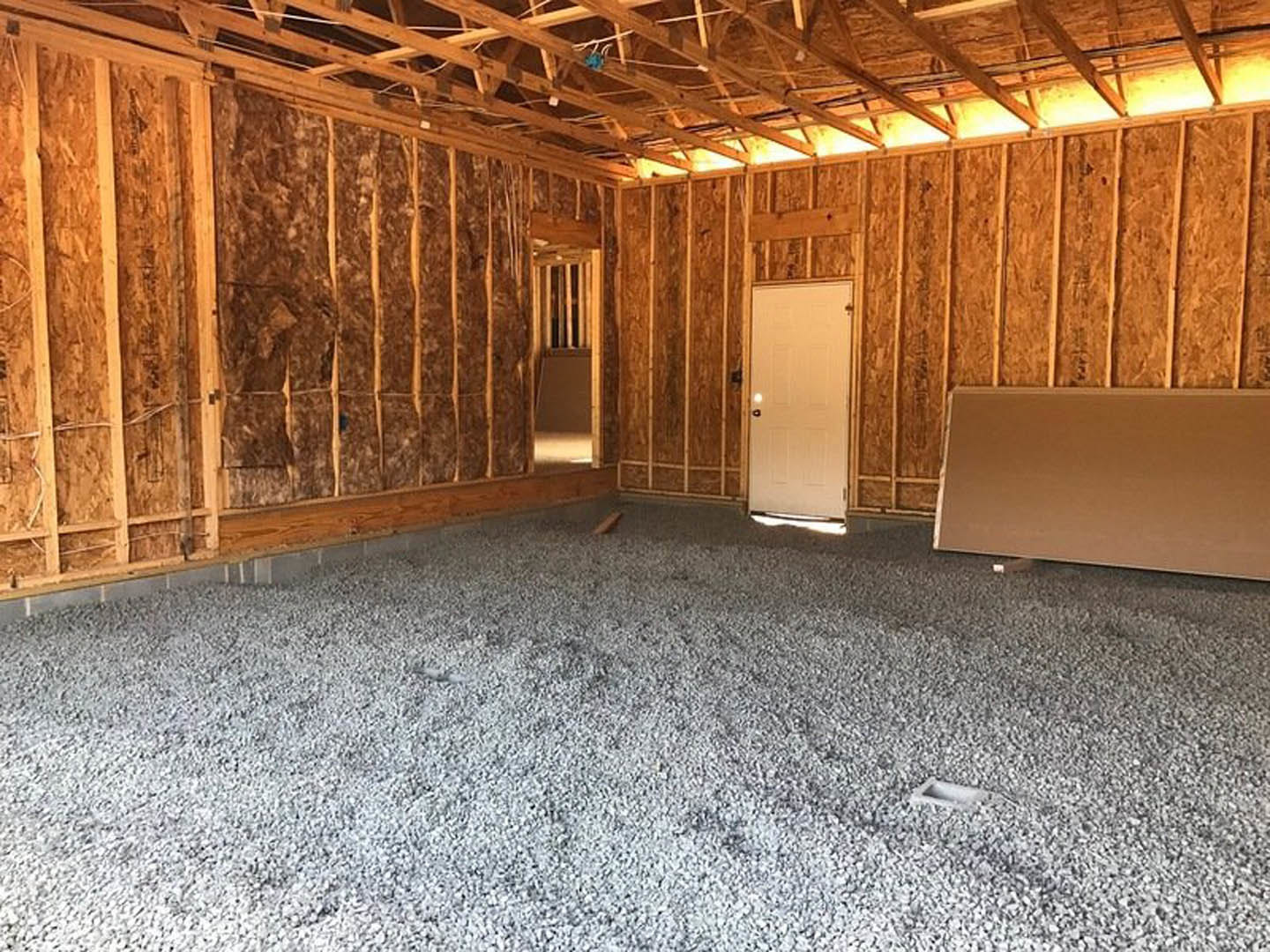 Carpeted room with white door, exposed wooden ceiling beams, and white wall.