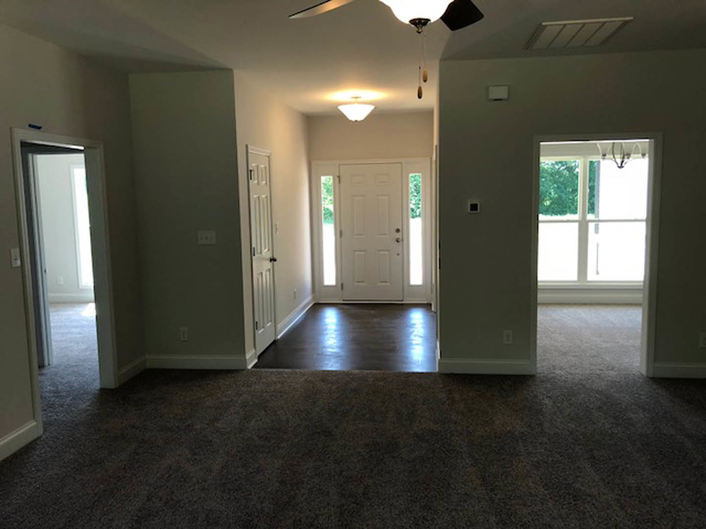 Laminate flooring, white walls, white paneled door with glass inserts, ceiling fan with light fixture, smooth white ceiling