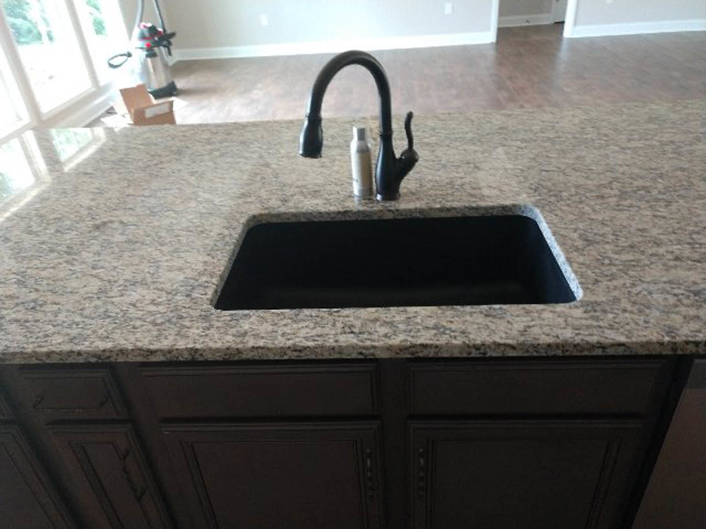 White kitchen countertop with undermount sink, matte black faucet, and white soap dispenser against tiled backsplash