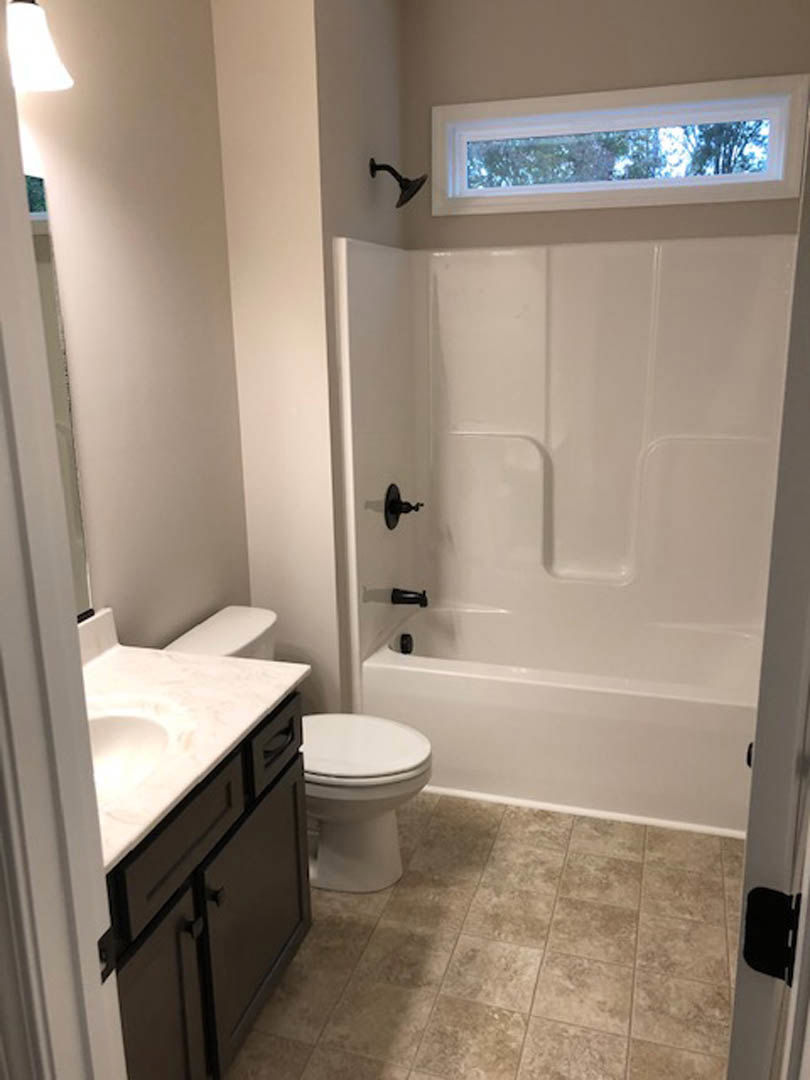 White porcelain toilet beside a rectangular sink with chrome faucet, light-colored tile flooring, and neutral wall tiles in a modern bathroom.