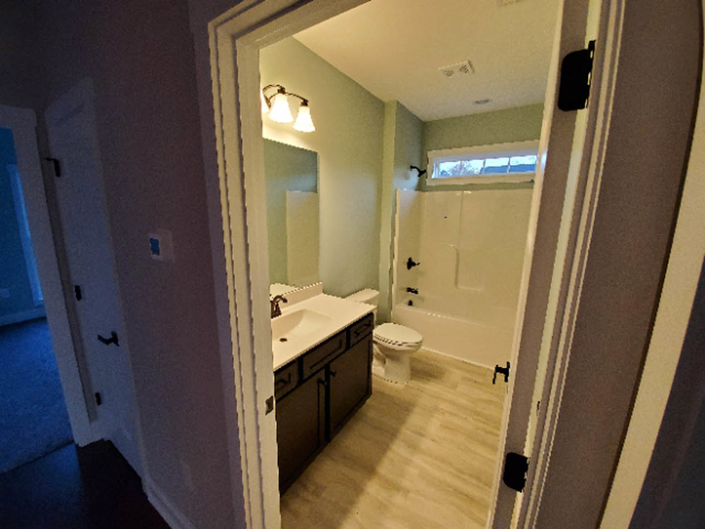 Modern bathroom with white ceramic sink, chrome faucet, and matching toilet on light gray tile floor, white tiled walls, and wooden door partially visible